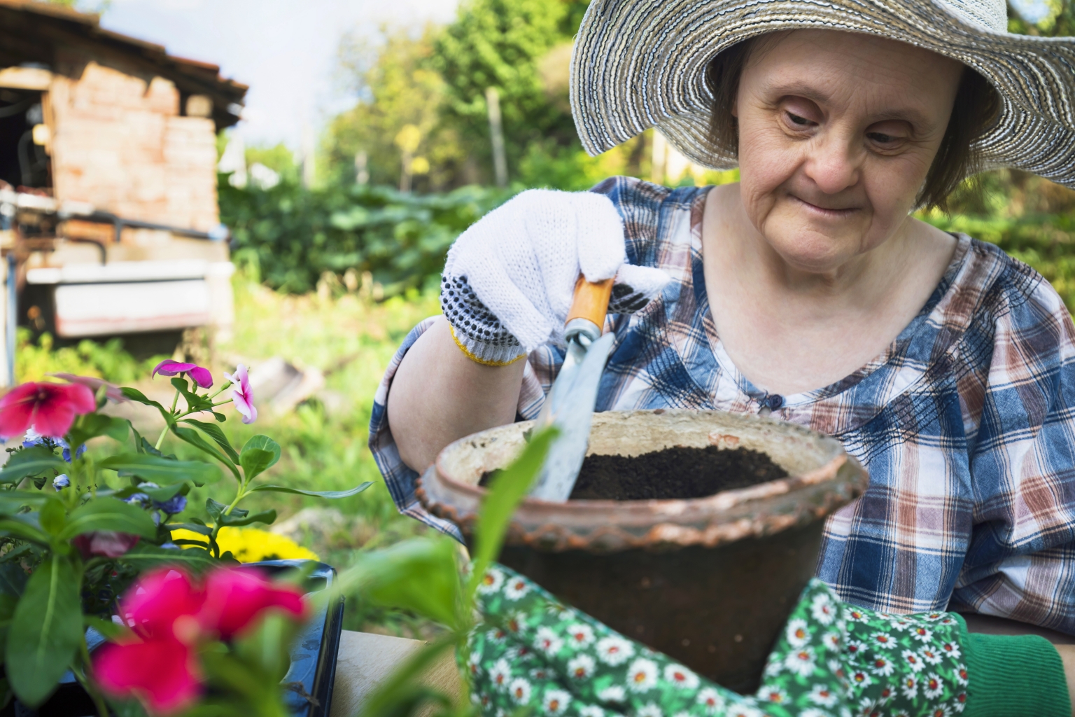 Happy woman with Down Syndrome ready to planting flowers. Activities